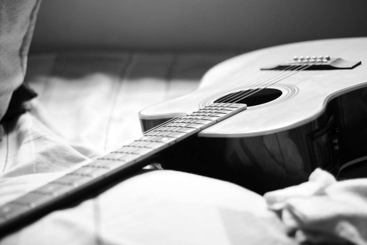 床上吉他的灰度摄影