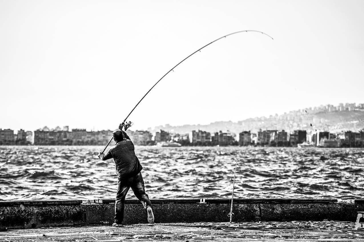人体近水面钓鱼竿的灰度摄影