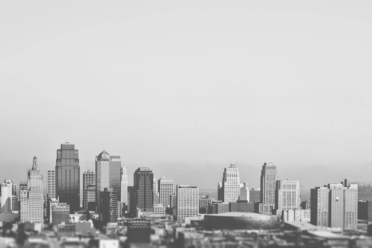 这张黑白图片展示了一个典型的美国城市的商业区和商业区一些中等大小的摩天大楼,一些低矮的建筑物和体育场都是可见的背景似乎有雾