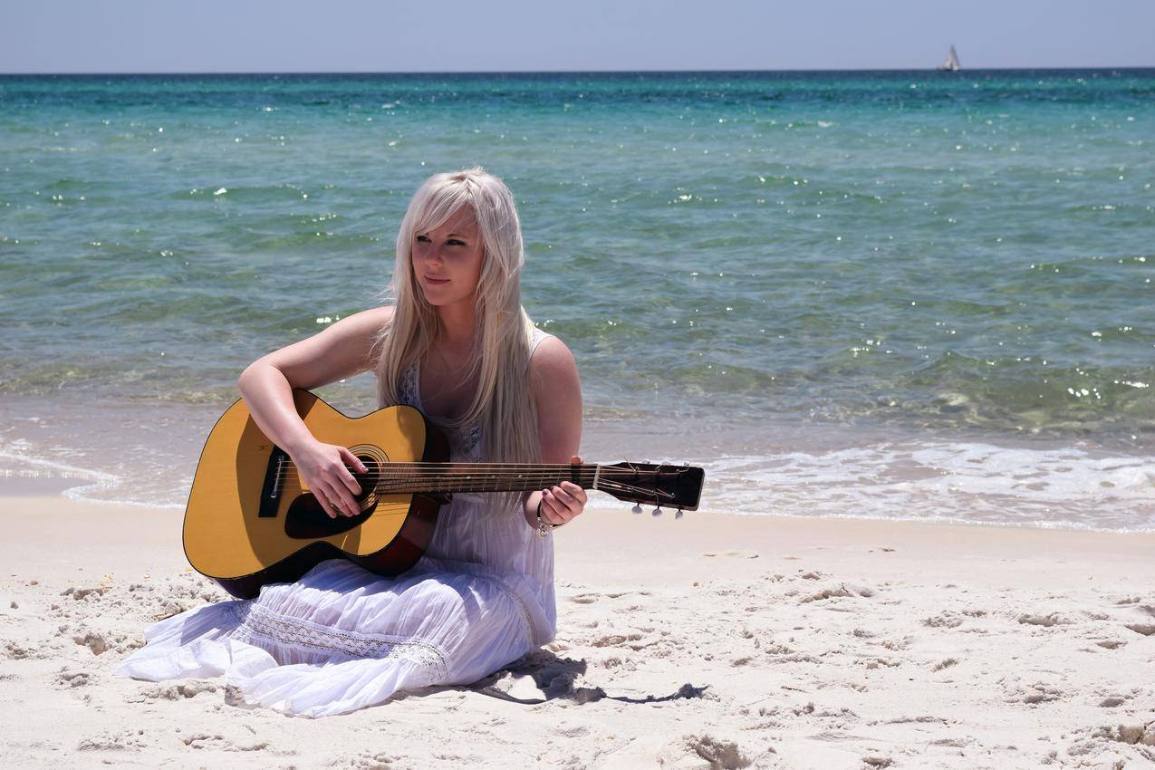 海边的白女人弹奏云杉顶无畏的吉他