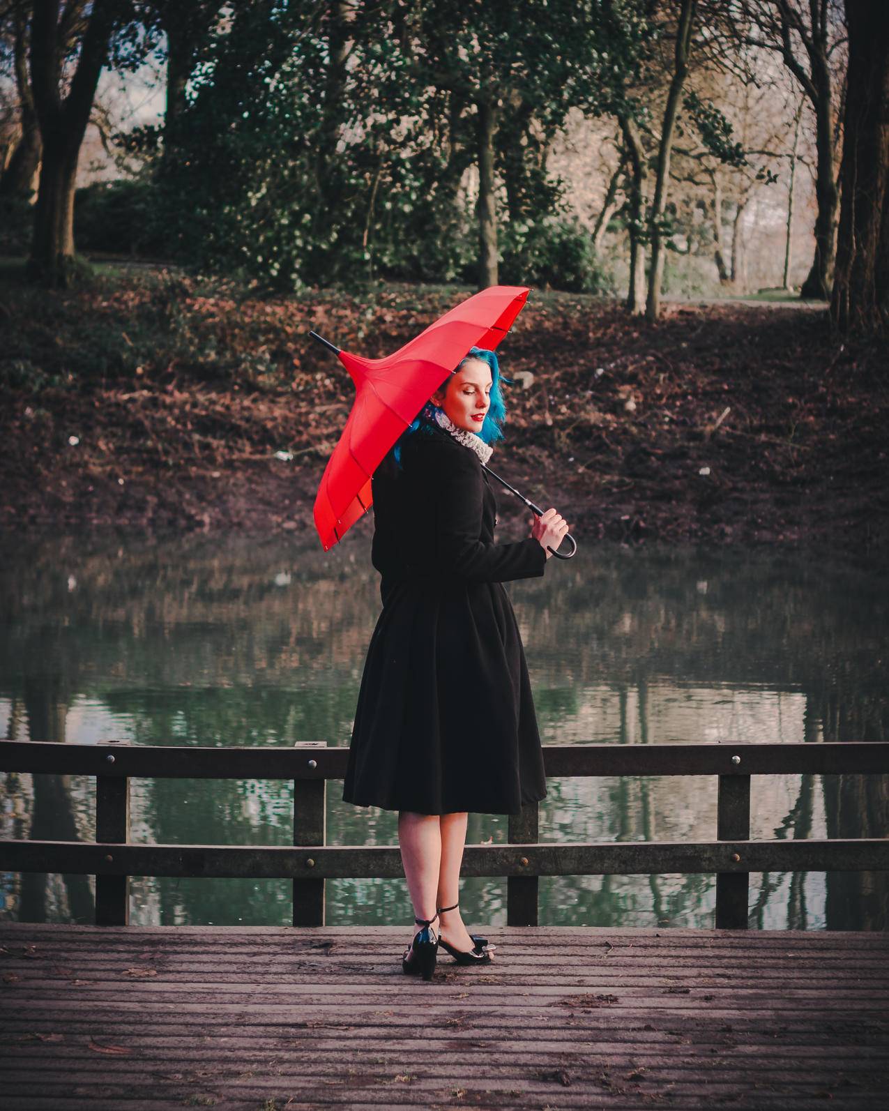 穿着黑色长袖礼服的女士手持红色雨伞