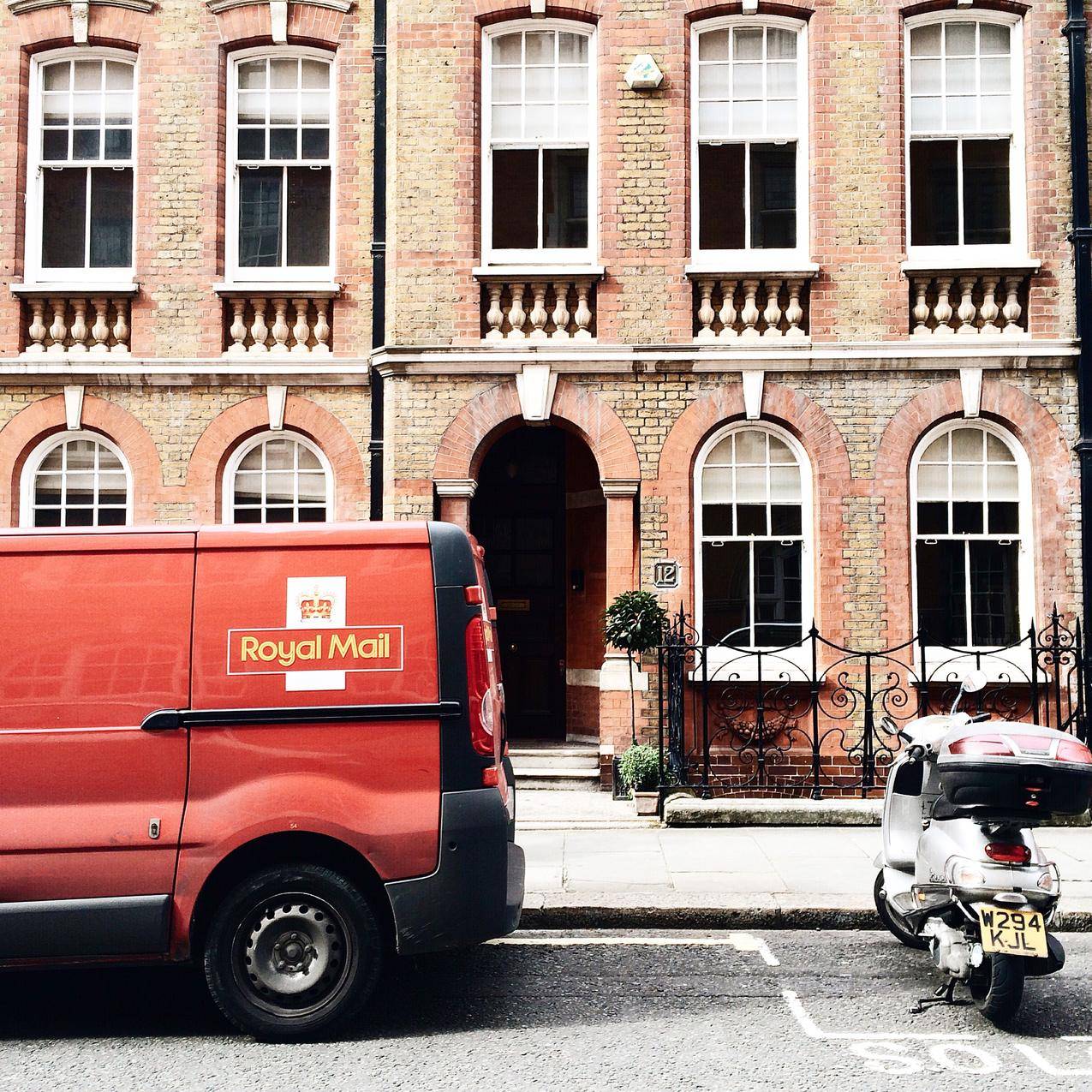 红色皇家邮政停在棕色砖房附近