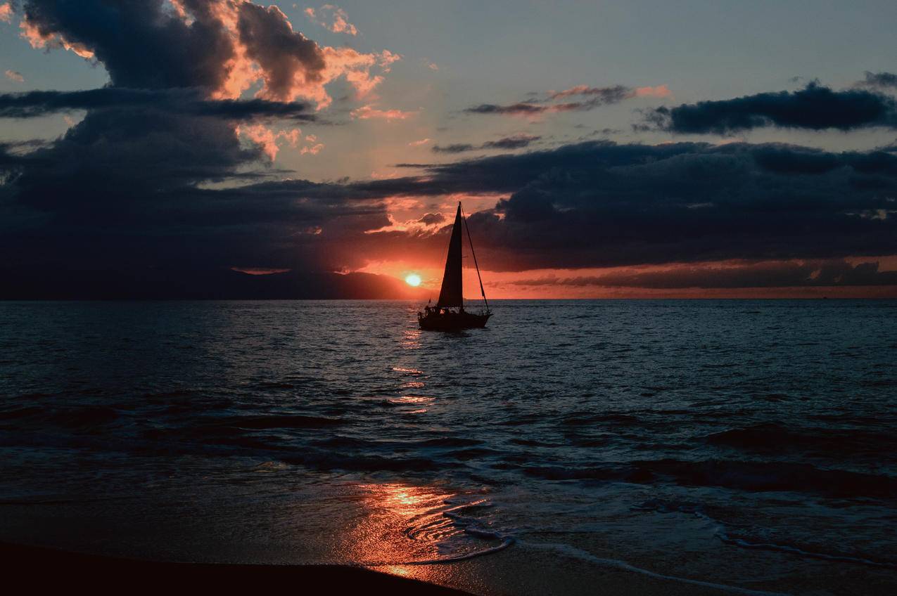 日落时水面上帆船的轮廓