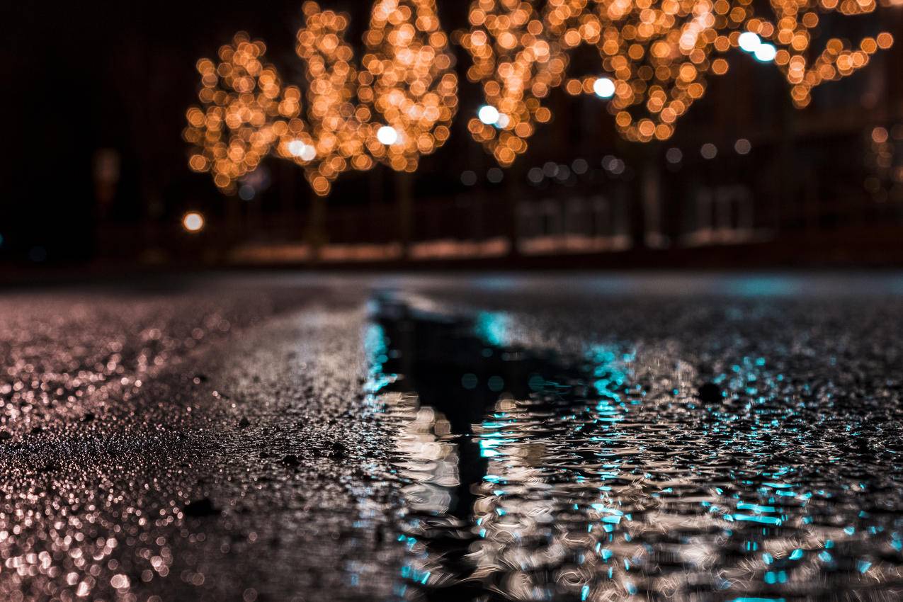 夜间城市路灯附近水滴沥青路面的选择性聚焦摄影