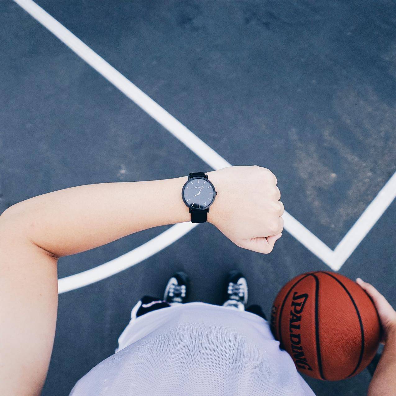 左手右手佩戴黑色圆形模拟手表,右手持篮球