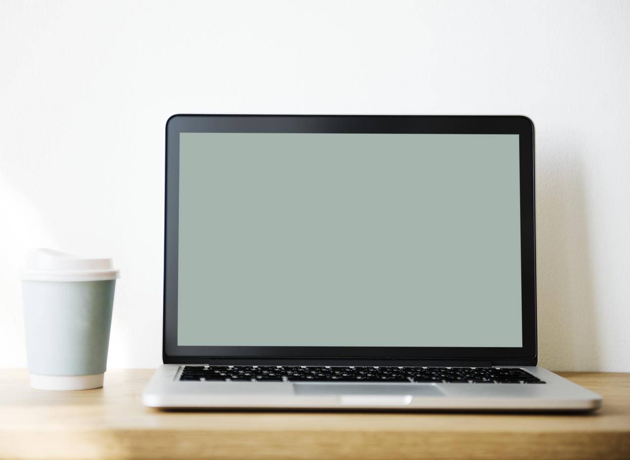 黑白笔记本电脑旁边的白色和茶色咖啡杯