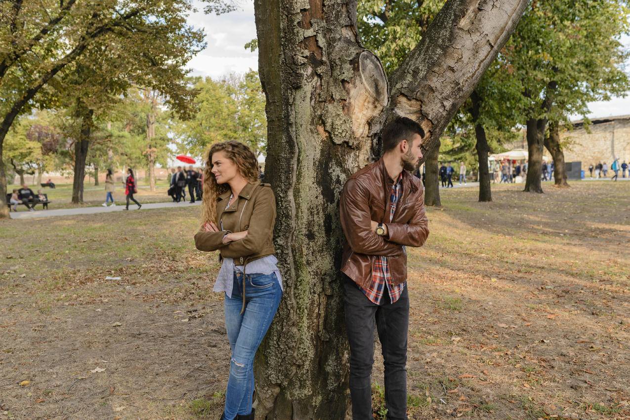 身穿皮夹克的男人和女人站在树下