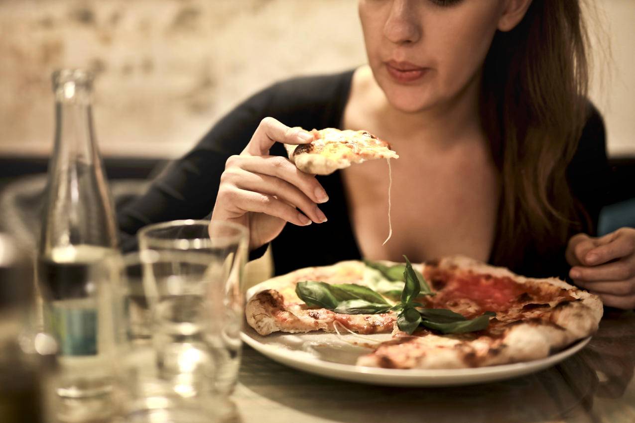 女人拿着格拉斯切成片的披萨席
