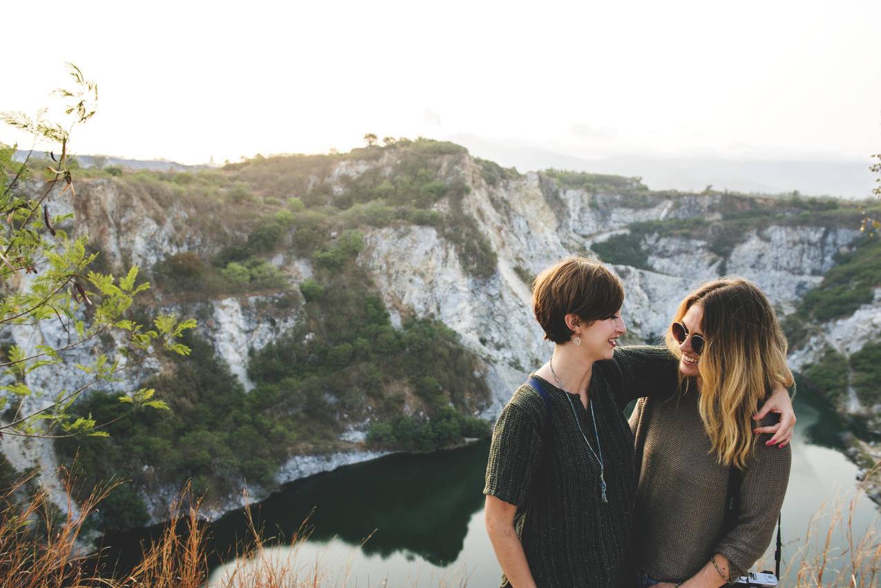 自然风景摄影素材两个人坐在山顶的悬崖边上欣赏着日出时分的自然景致