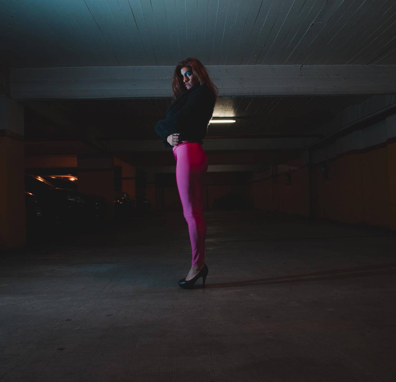 妇女穿着黑色衬衫和粉红色绑腿在停车场的高清图片