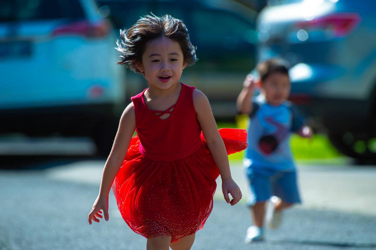 穿着红色连衣裙的女孩在街上奔跑的照片
