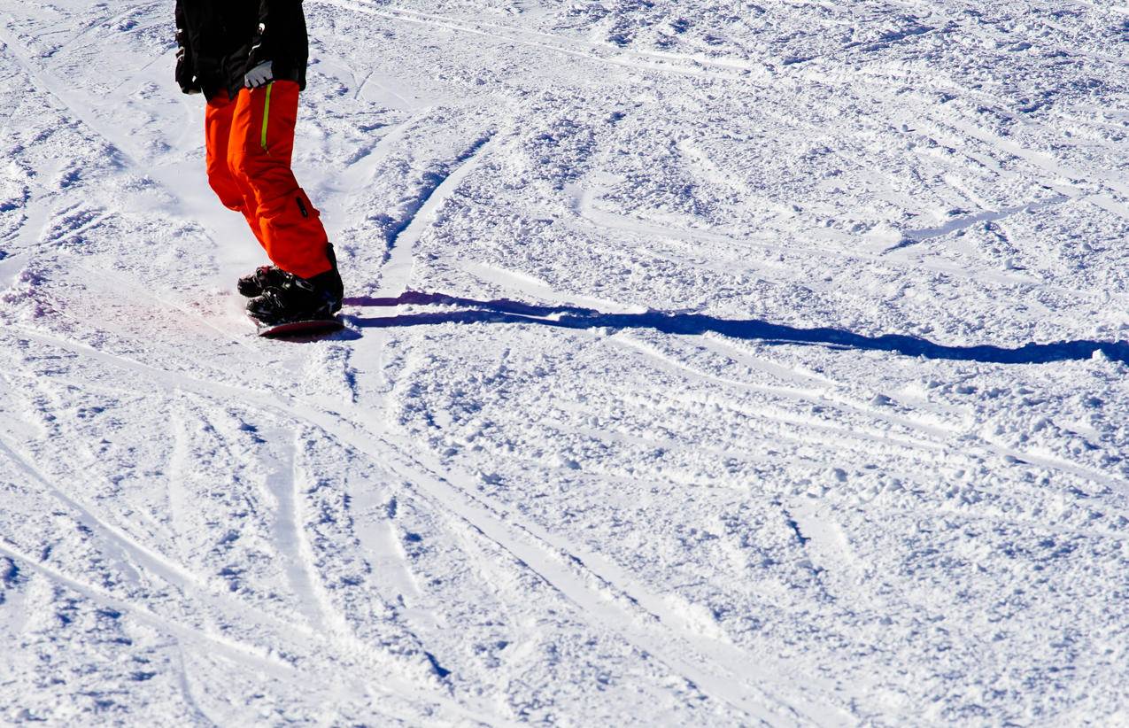 穿黑顶橙色裤子骑雪板的人的图片