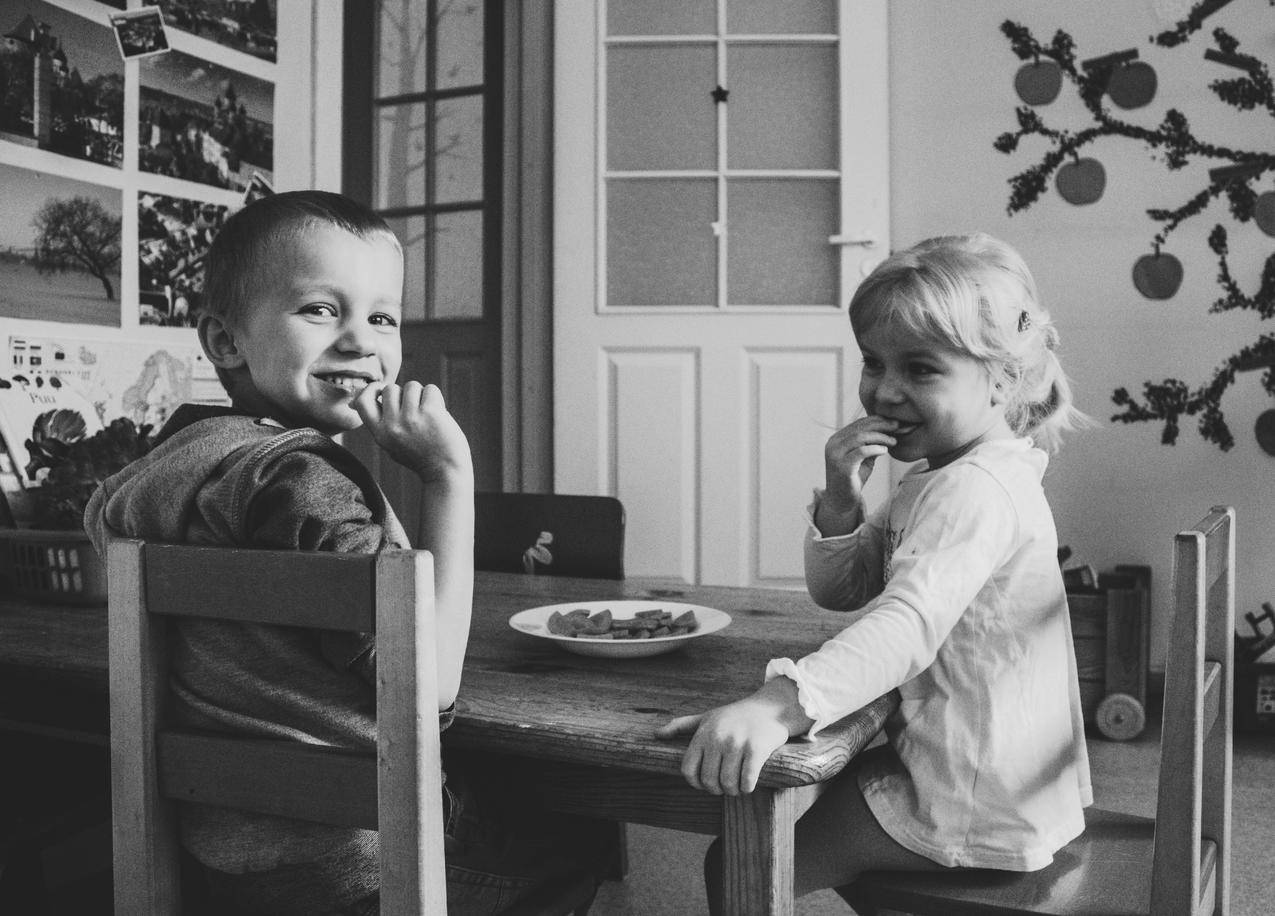 两张坐在餐桌椅上的小孩的灰色高清大图