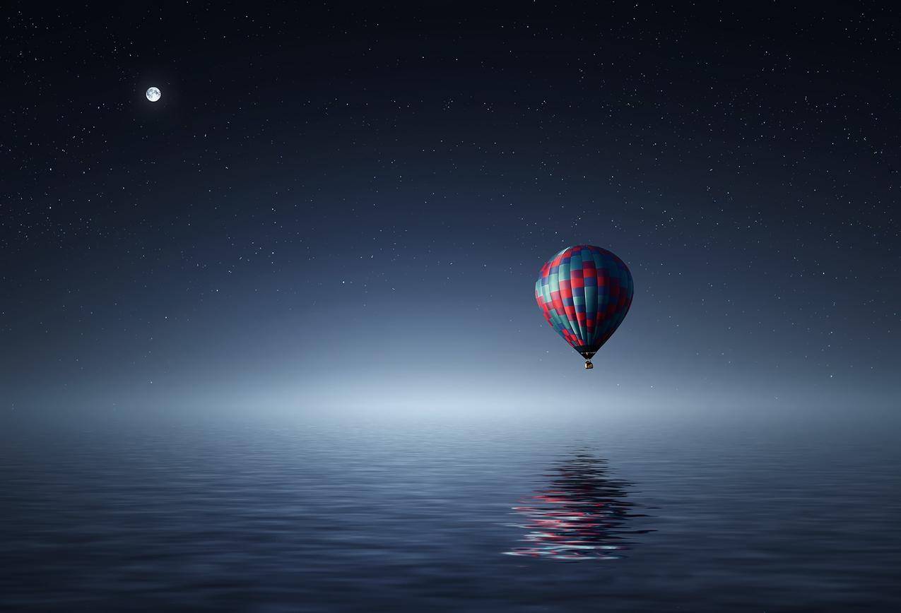 夜间红色和蓝色热气球漂浮在水体上