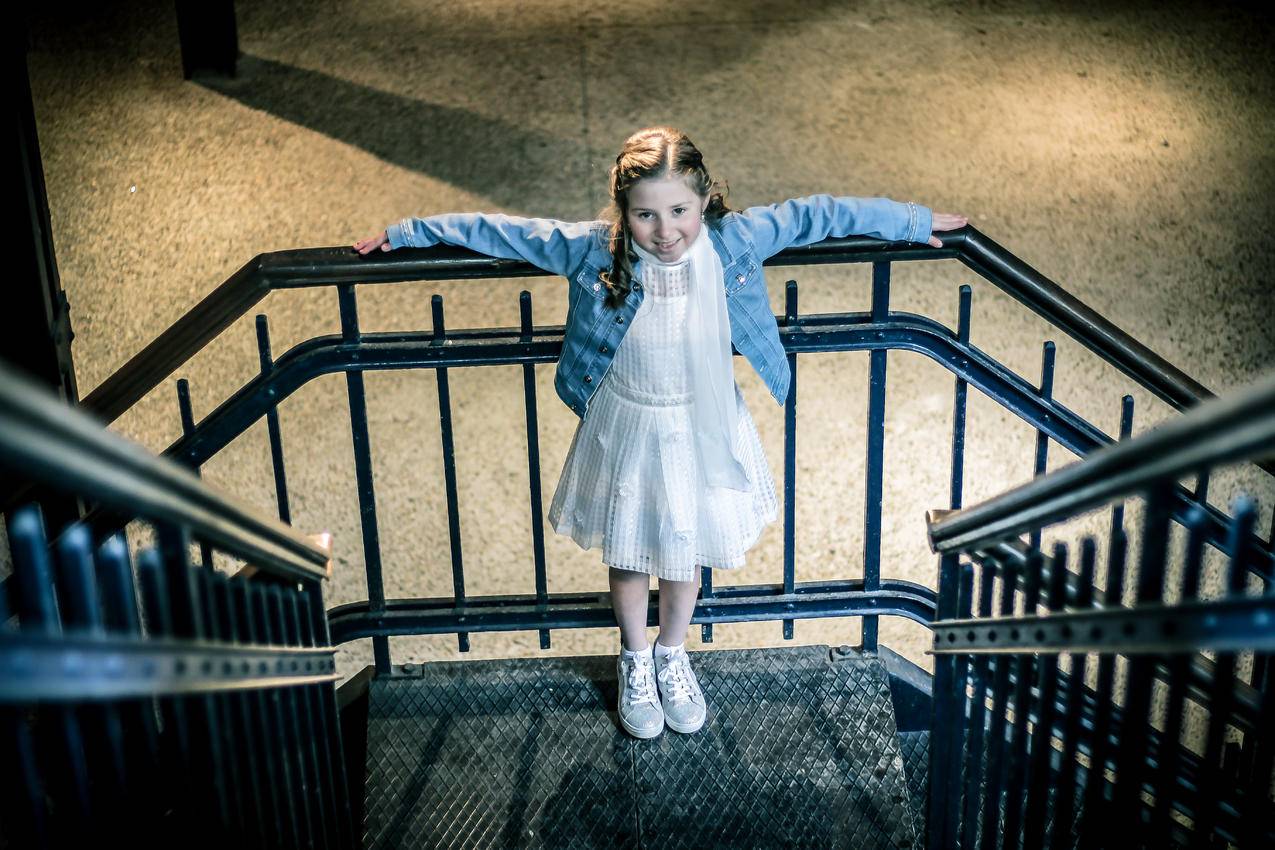 夜间穿蓝色夹克衫和白色长裙站在栏杆上的女孩