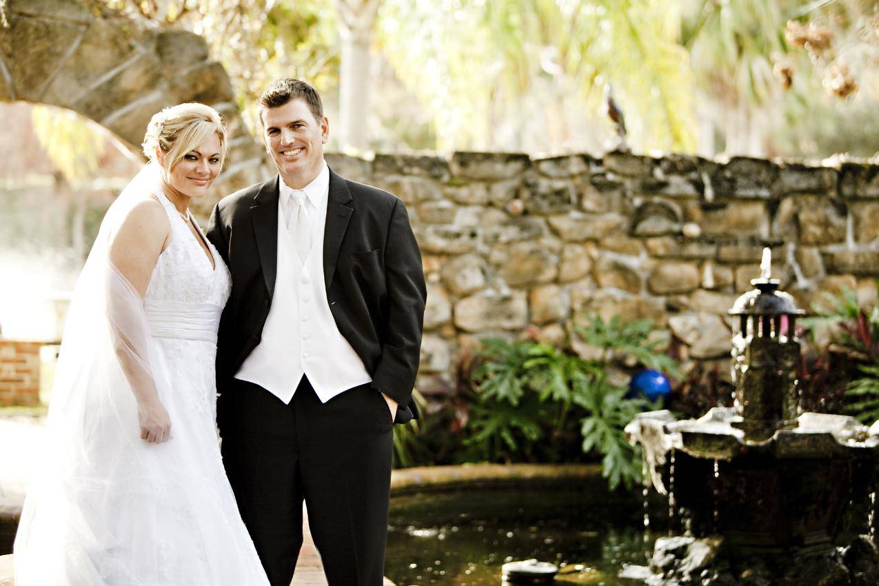 男人和女人在他们的婚礼装备棕色墙壁在背景附近的喷泉和池塘白天
