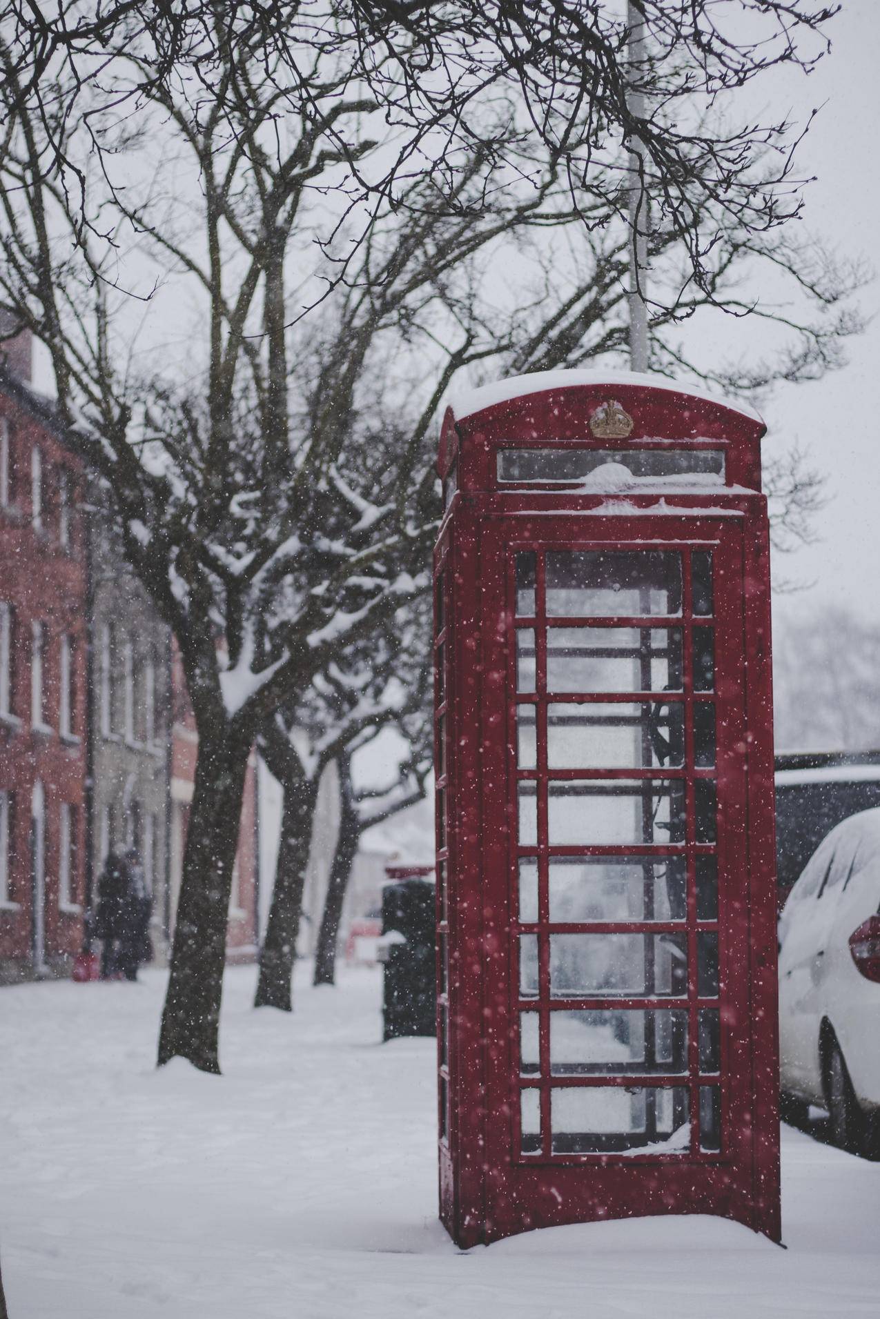 带雪的人行道上的红色电话亭