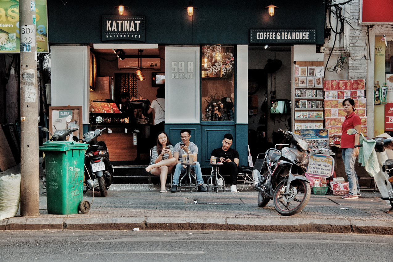 三人坐在靠近摩托车咖啡厅的椅子上