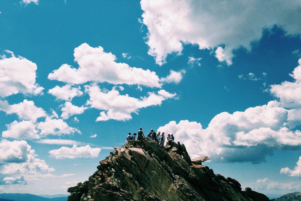 蓝天白云与登上山顶的人群图片