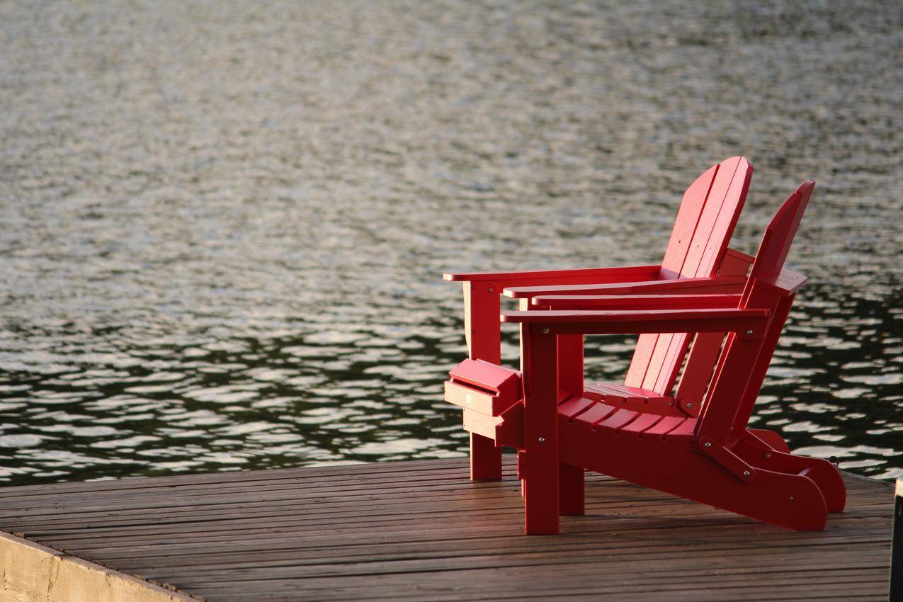 红色木制躺椅在棕色的木板道上靠近水的白天