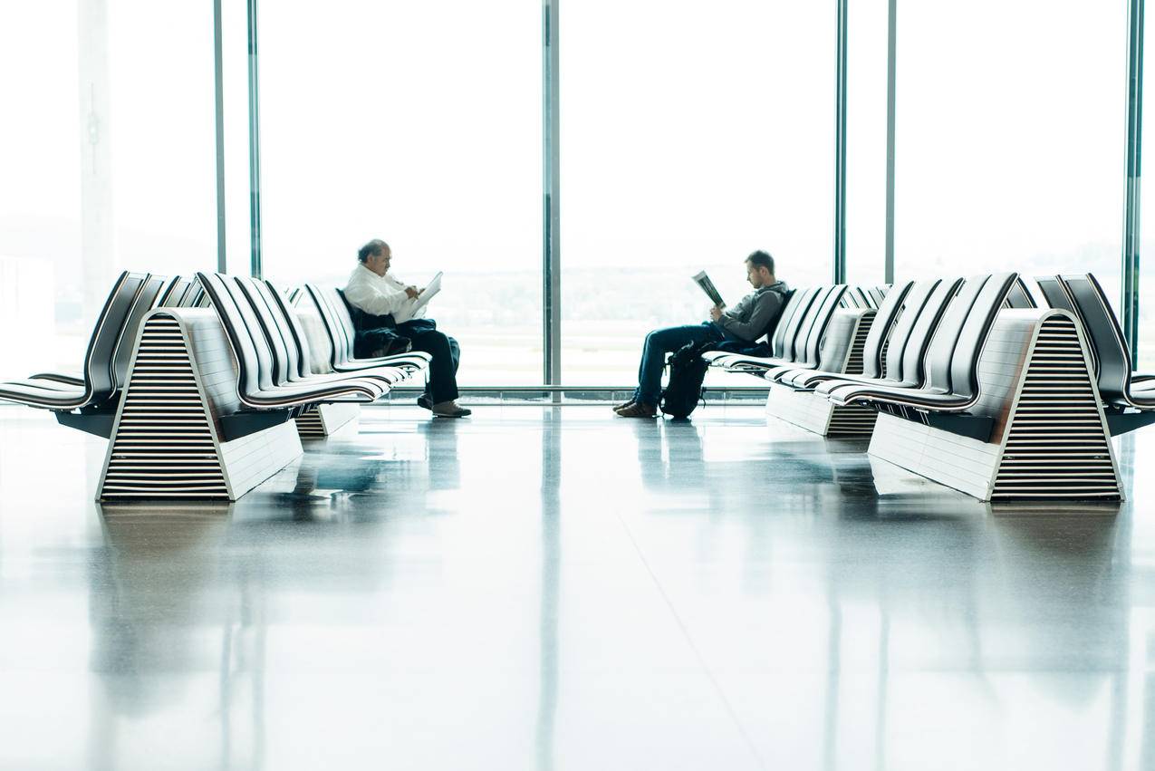 机场候机区两名男子坐在白帮椅前