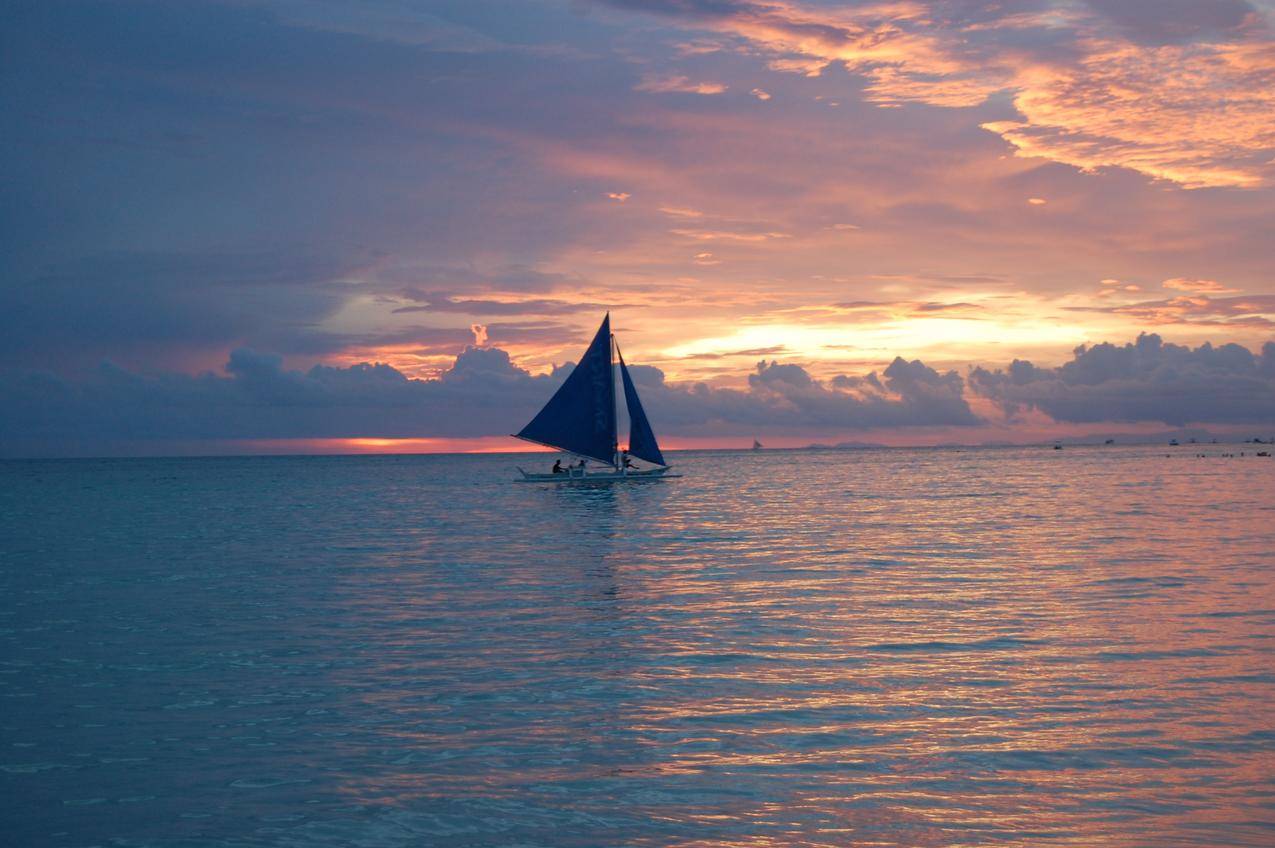 傍晚的日落云彩与海上帆船图片