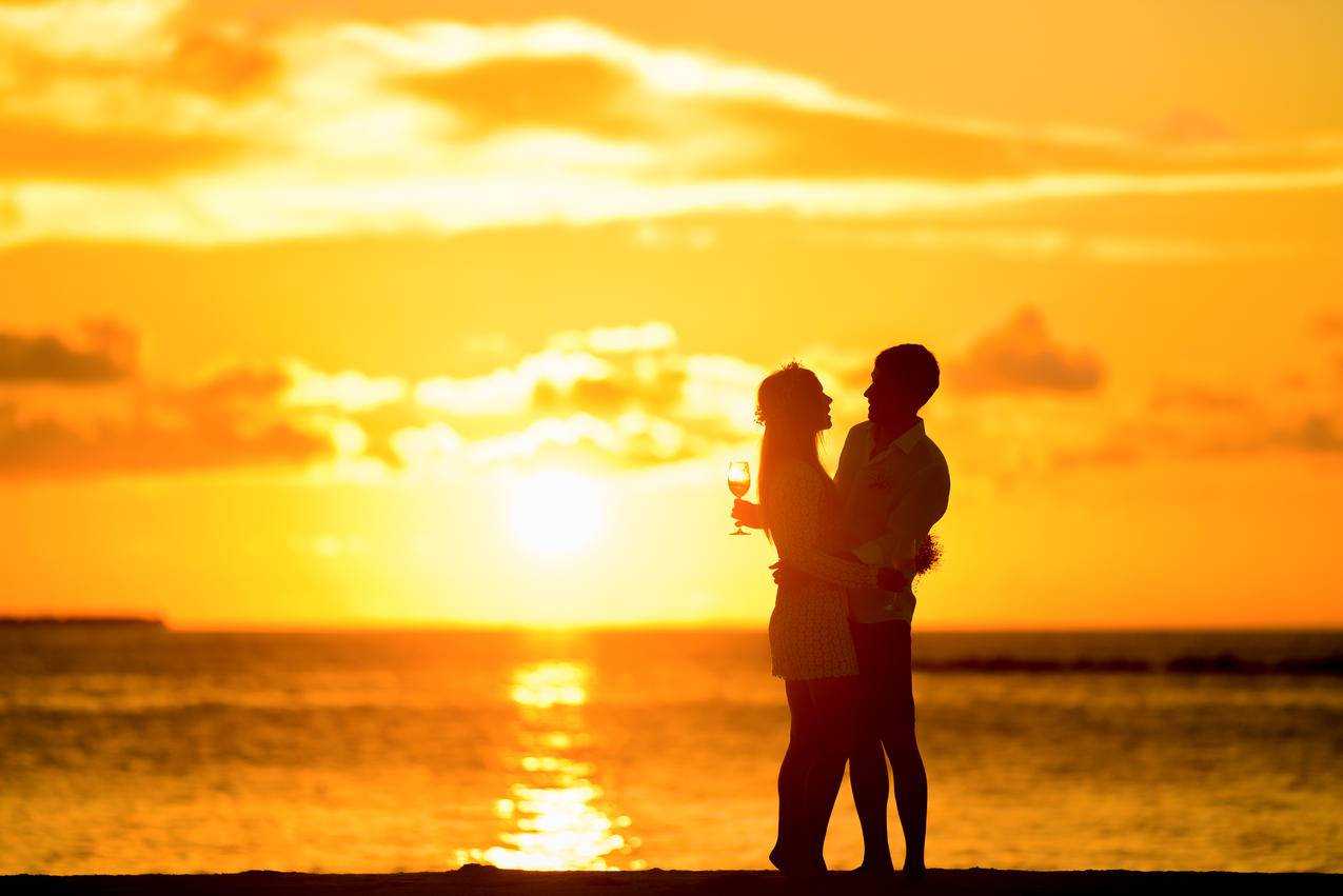 站在海边的情侣在夕阳中拥抱