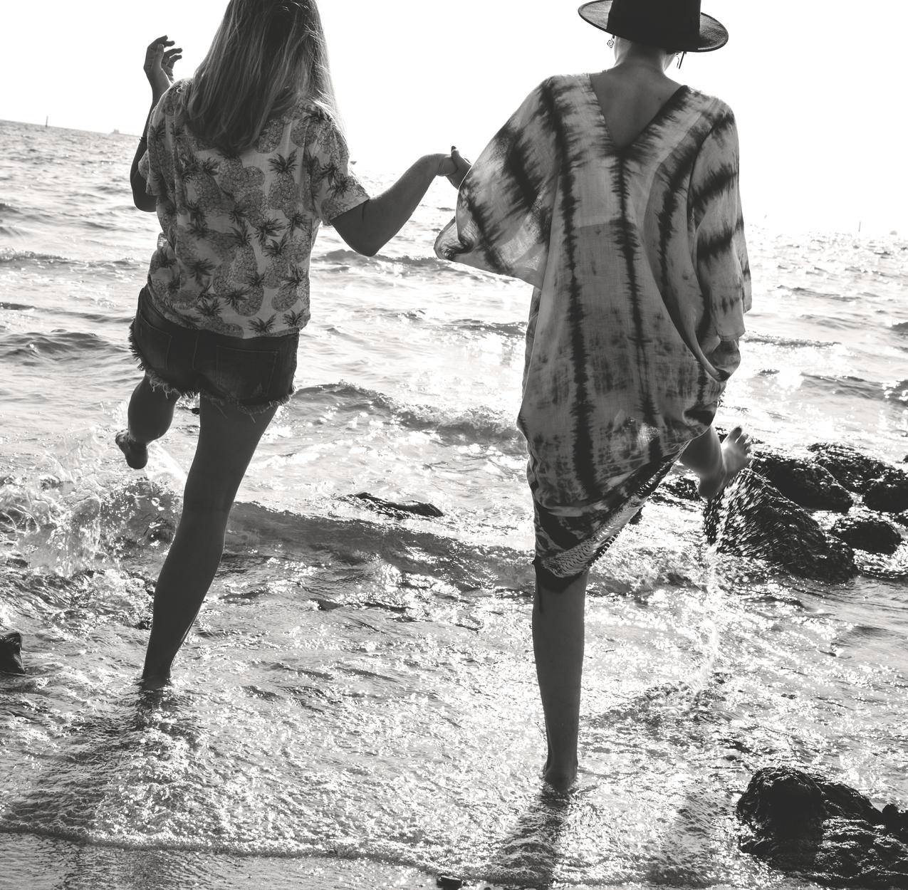 2名女子在海边行走时手拉手的灰度照片