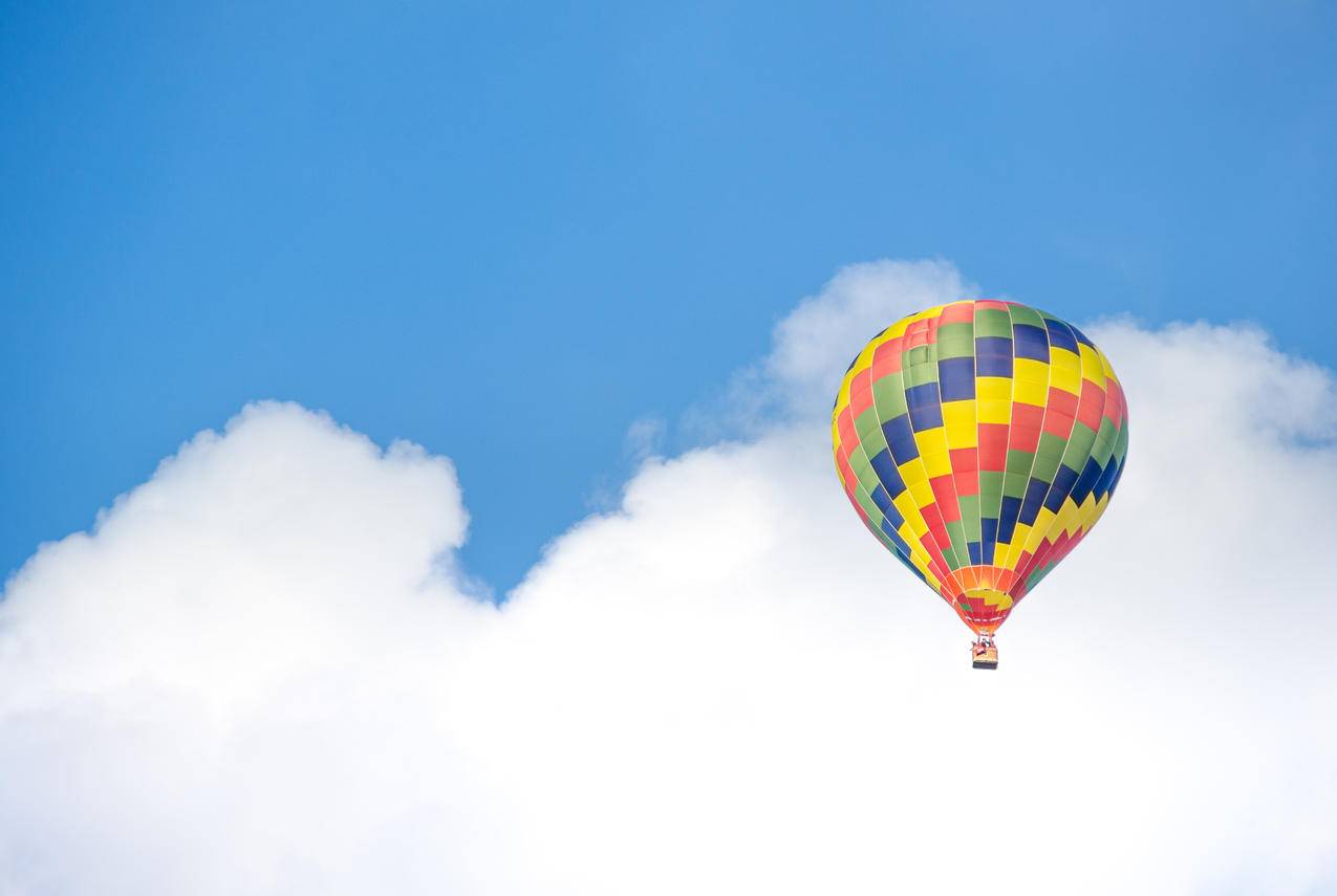 蓝绿色的热气球在白云附近飞行