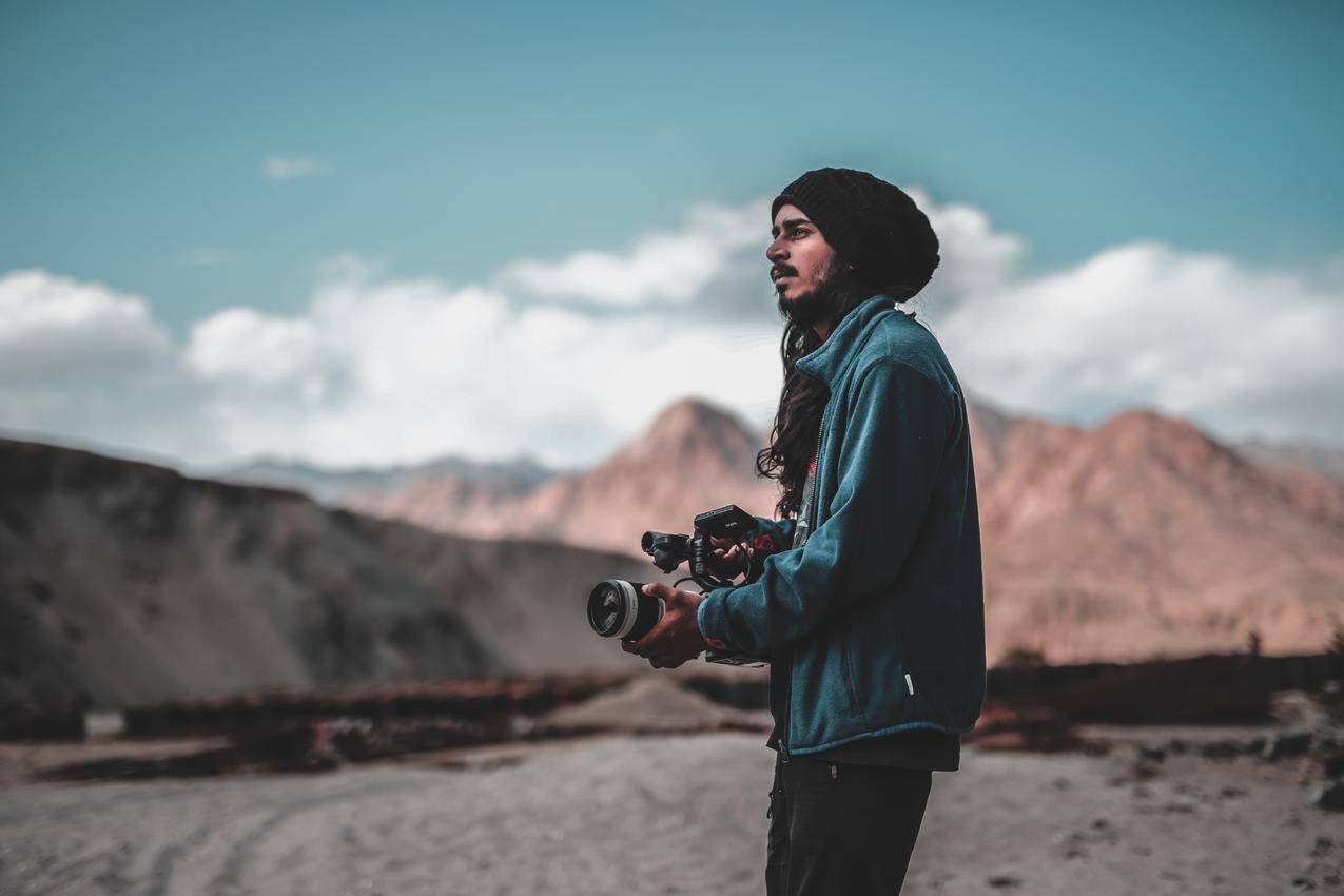 穿着外套的人在沙漠中手持数码相机