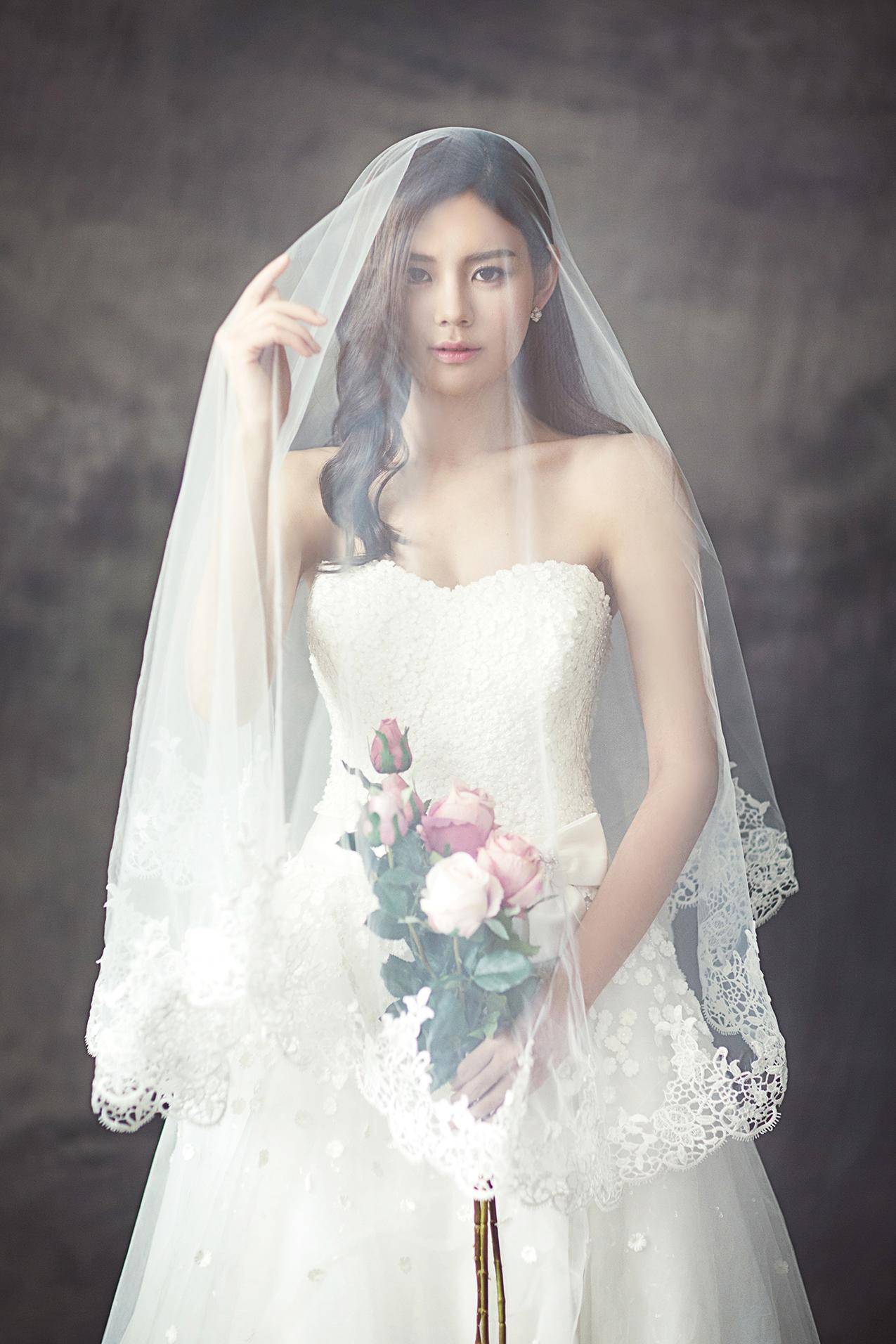 穿着白面纱的玫瑰花束婚纱