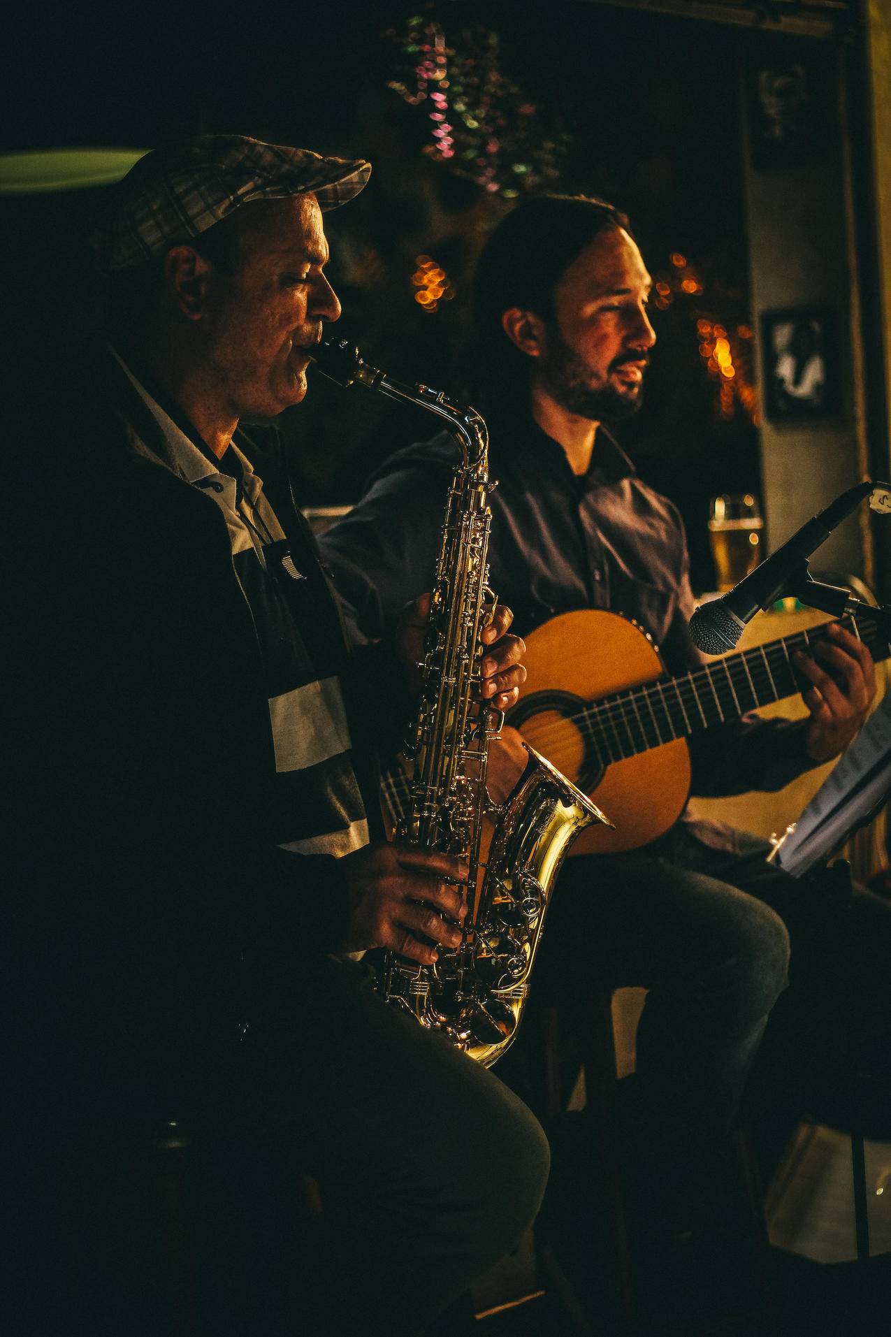 两名男子夜间演奏萨克斯管和原声吉他