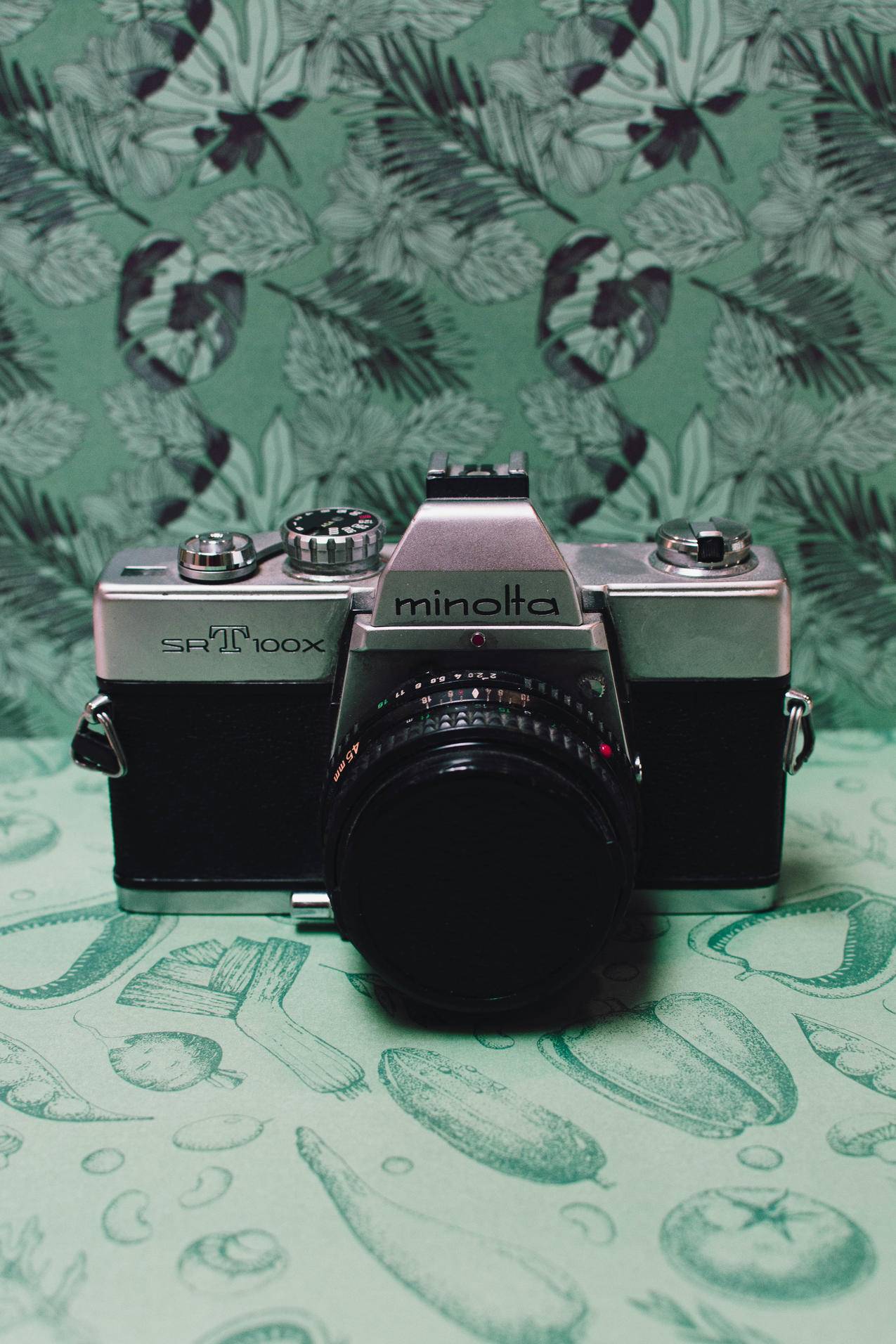 绿色花卉纺织品上的黑白胶卷相机