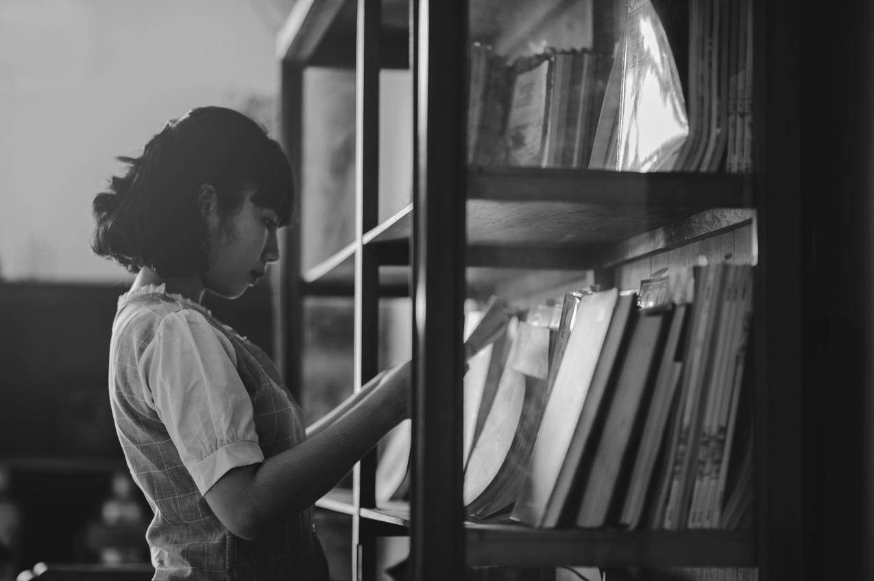 一个女人在图书馆里拿着书的灰色高清大图