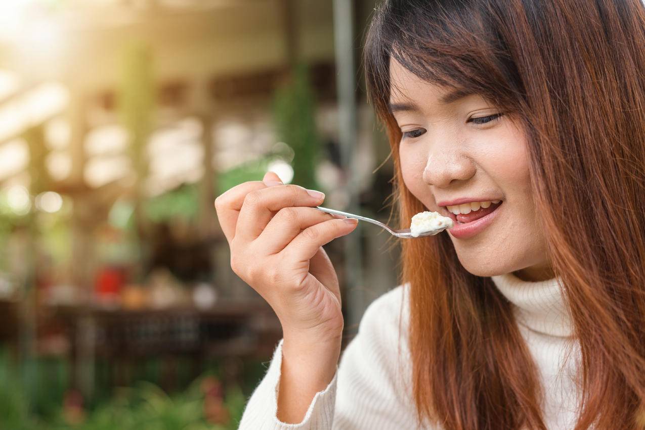 拿着勺子吃白食物的女人