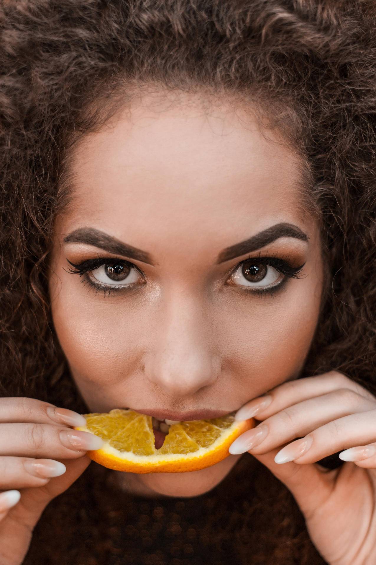 一个女人吃橙色的特写摄影