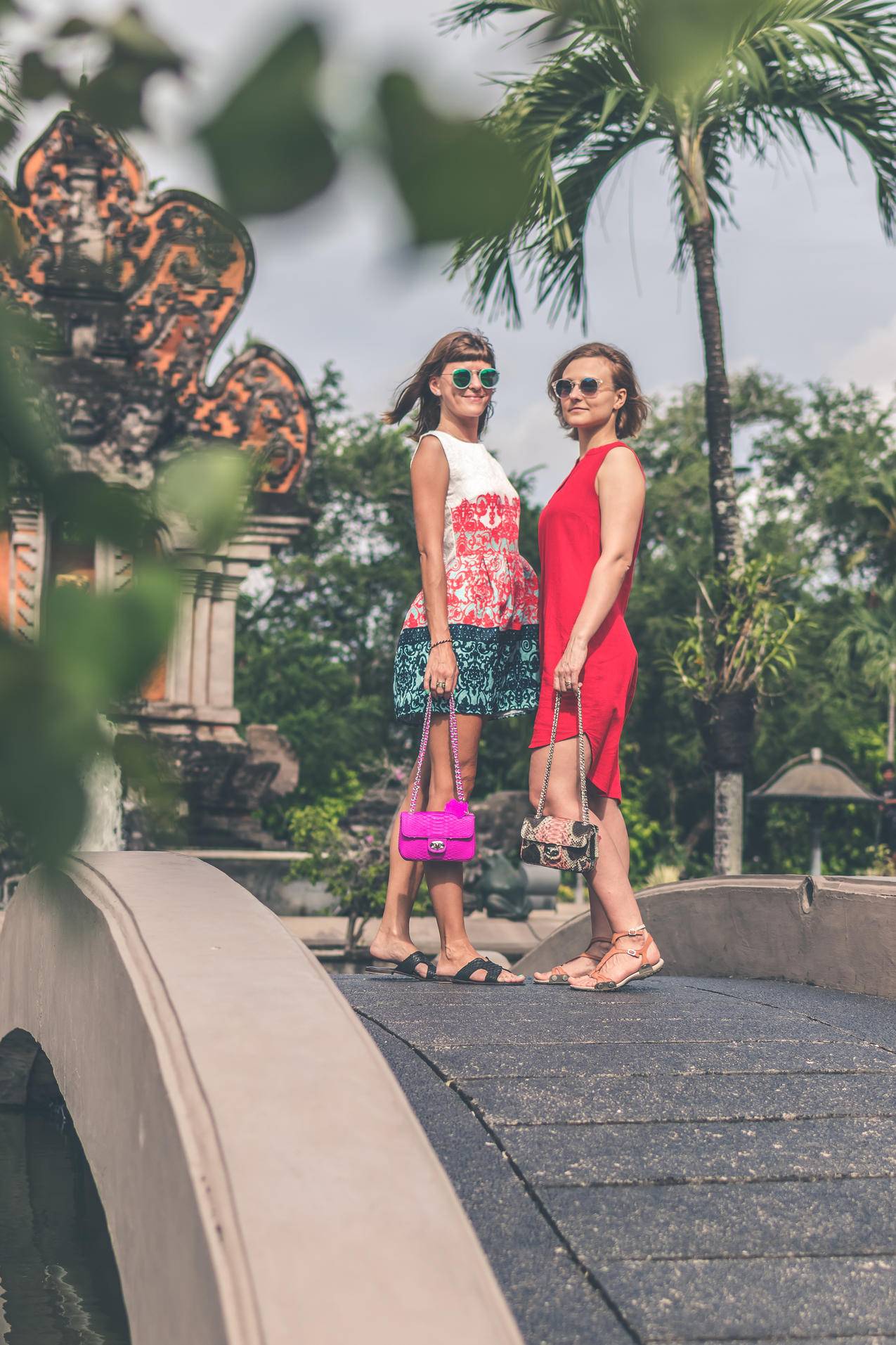 两位戴墨镜和手提包站在脚桥上的妇女