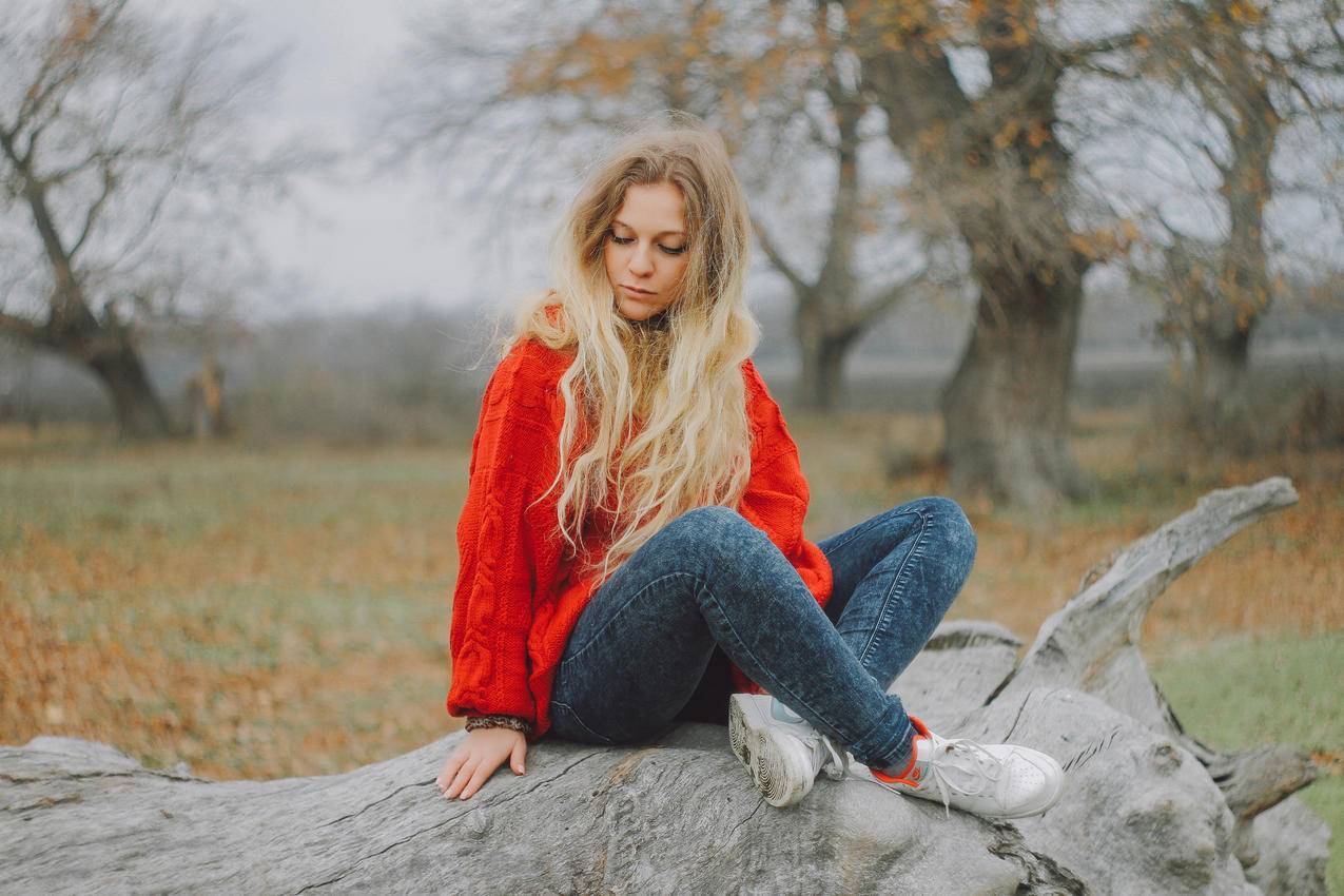 穿着红色毛衣的女人坐在树上