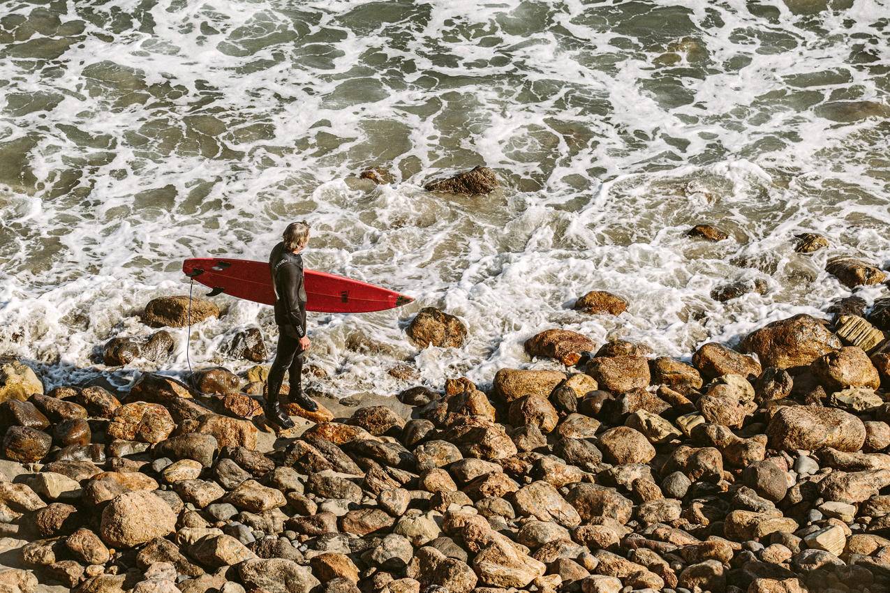 Man,Wearing,Wetsuit与海岸上的红色冲浪板