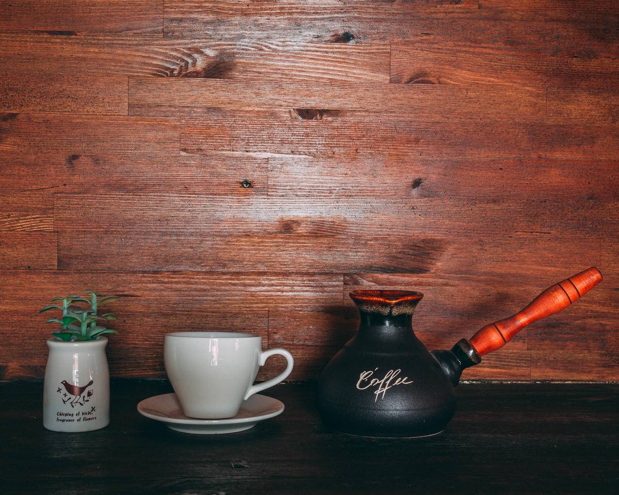 黑色和橙色土耳其咖啡壶在茶杯和茶碟附近