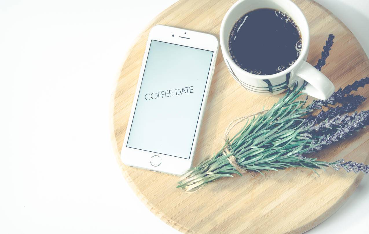 咖啡和鲜花旁边的iPhone
