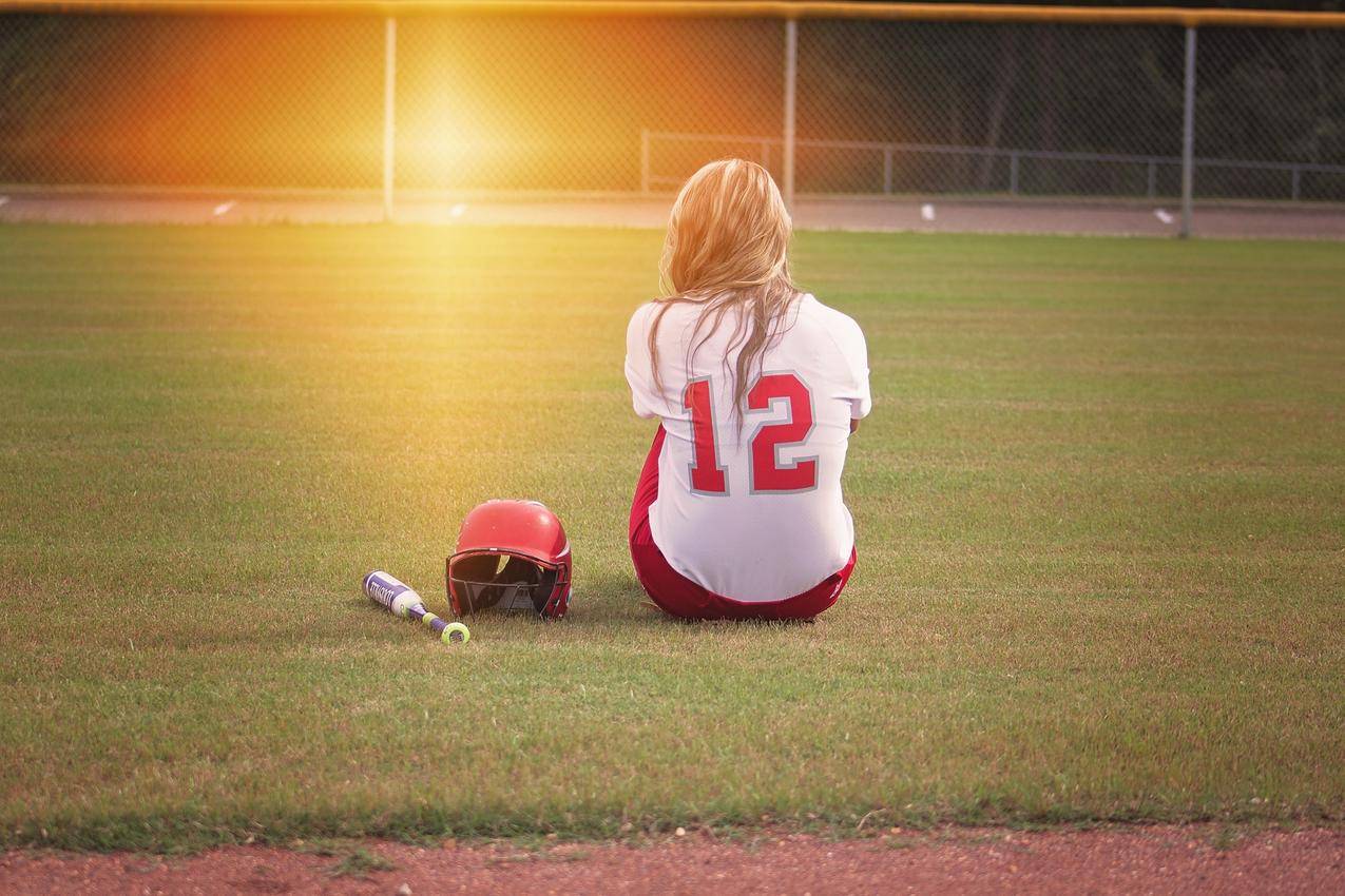 坐在草地上的女棒球运动员