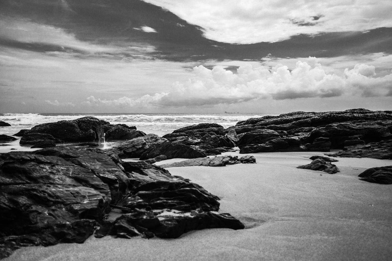 白天海岸岸边岩石的灰度摄影