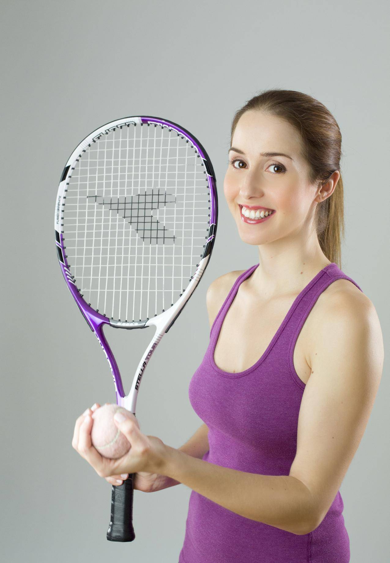 女子身穿紫罐顶夹紫白球拍和草地网球