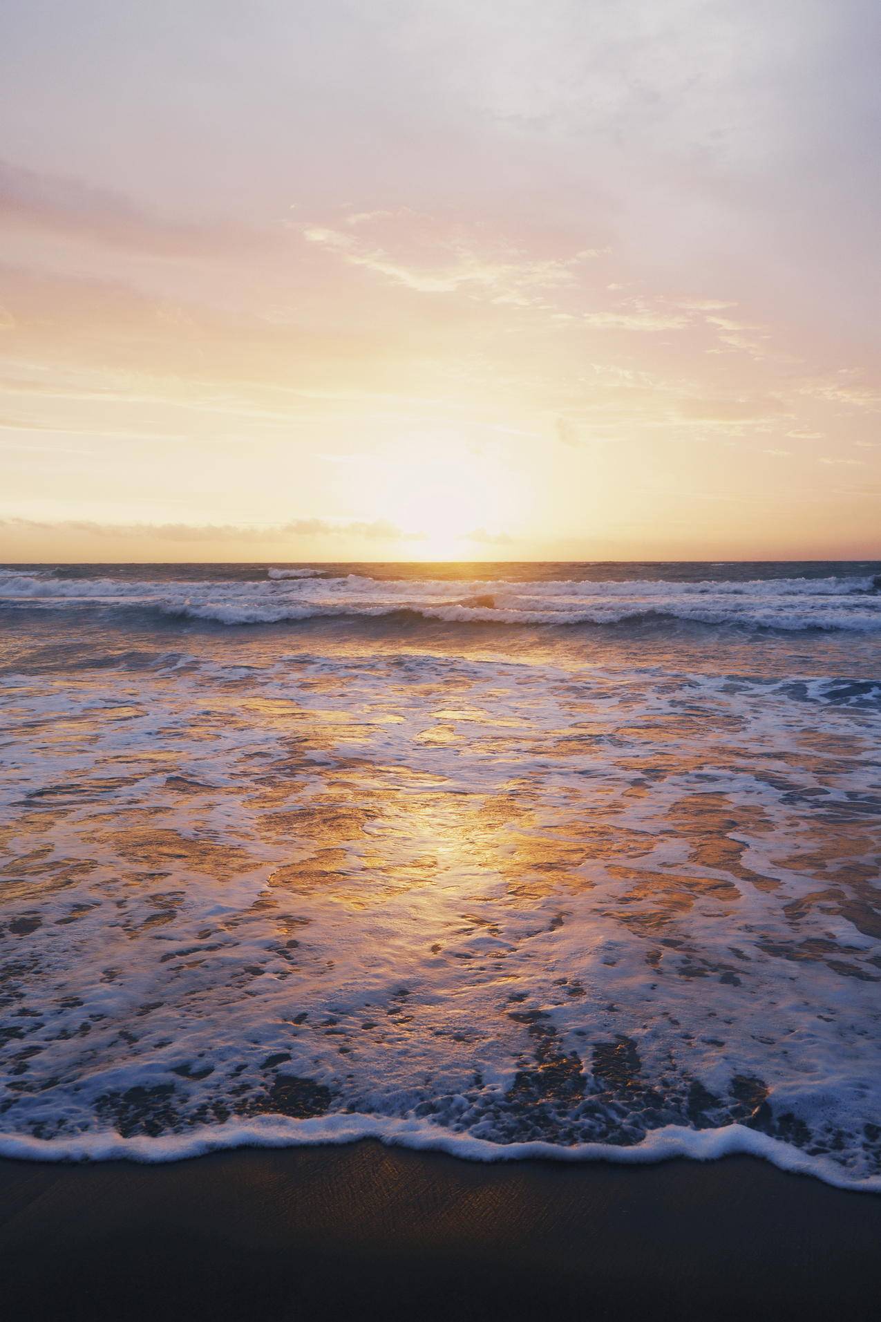 日落期间海岸附近海浪的图片