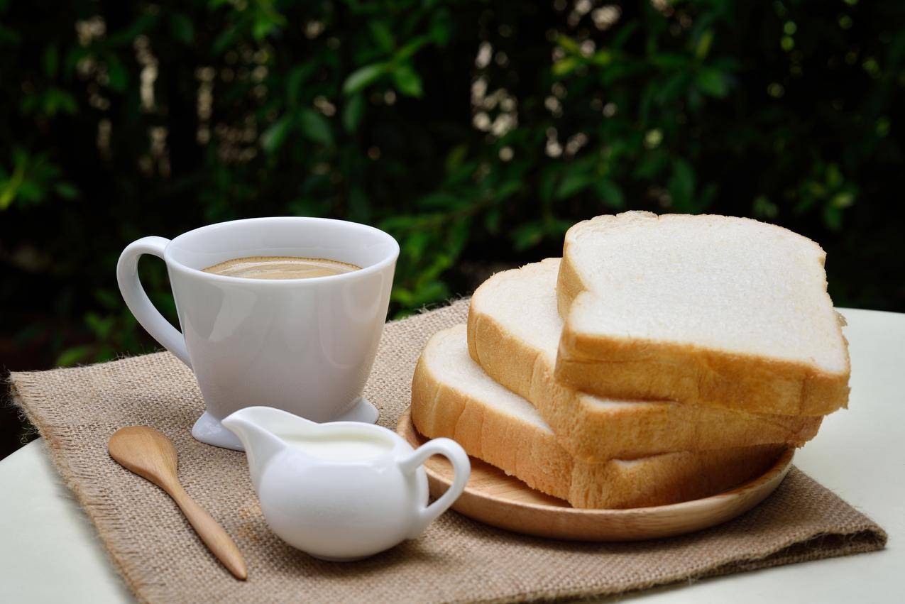 白色陶瓷咖啡杯旁的3片面包