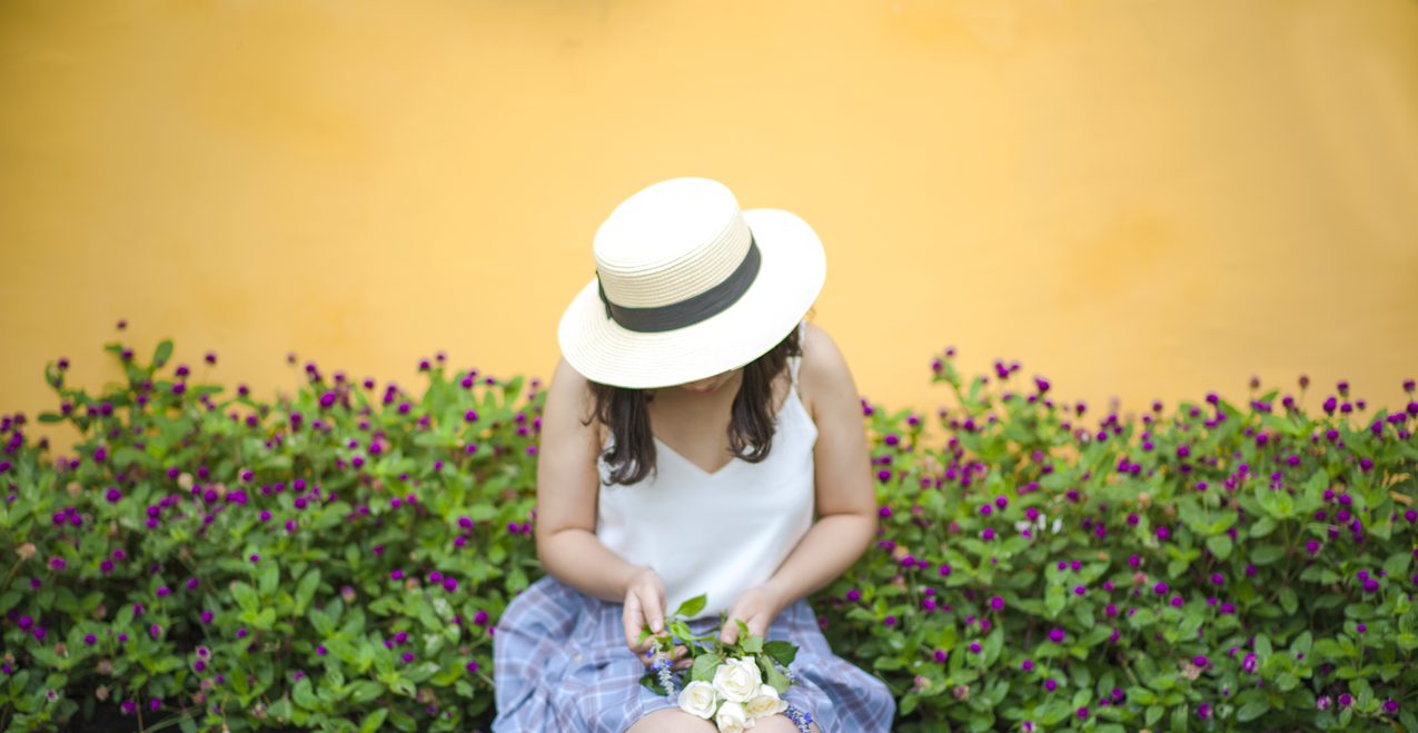 坐在花圃旁的女人捧着一束白玫瑰