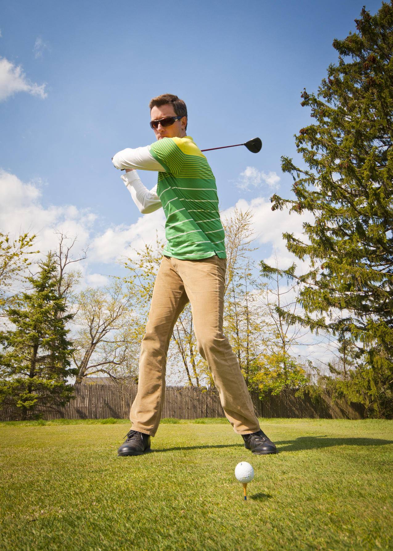 男子身穿绿色和白色条纹长袖衬衫举行黑色高尔夫俱乐部