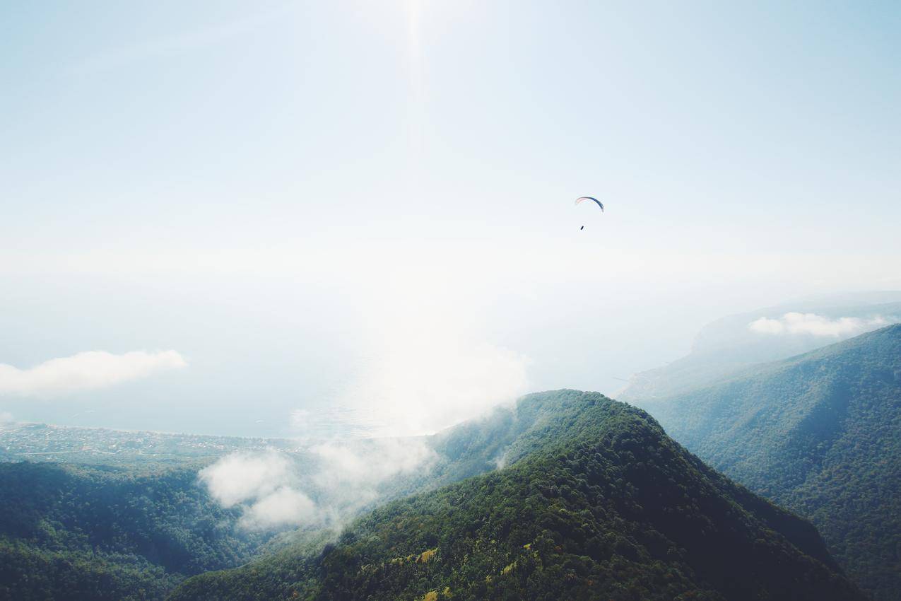 绿色植被的山峦云雾与滑翔伞运动