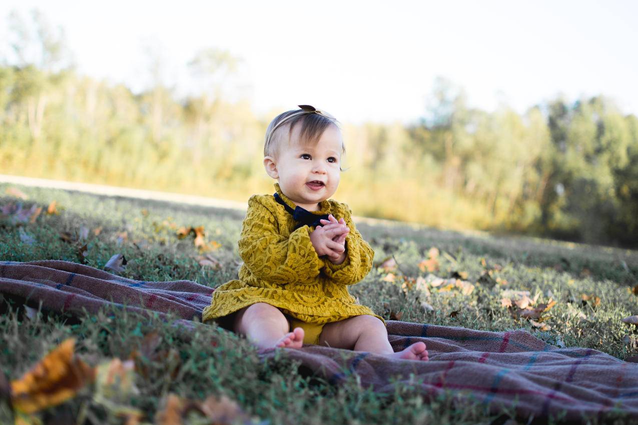 婴儿穿黄钩针长袖礼服坐在棕色织物上